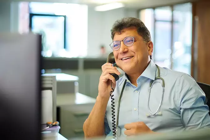 male GP on the phone and smiling using hosted telephony system