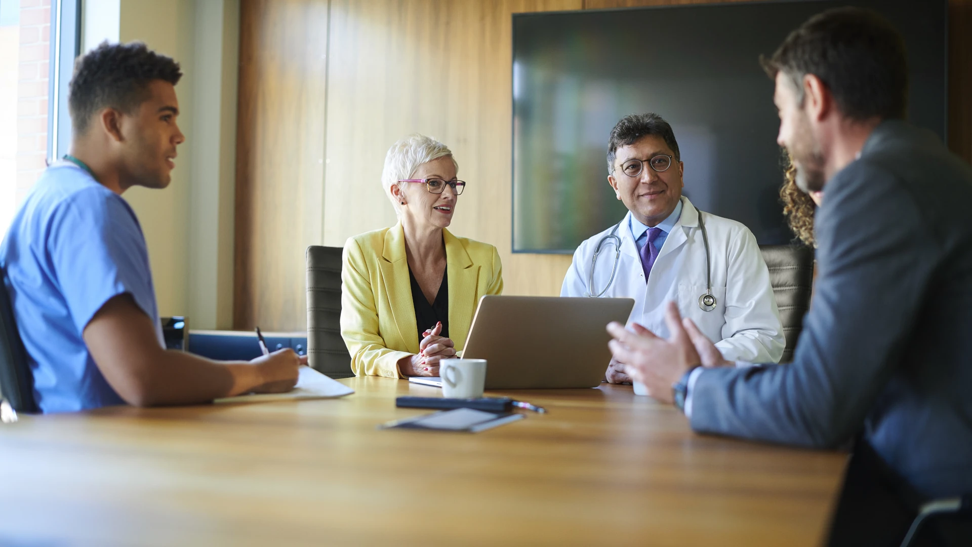 
                      a group of people having a meeting around a table
                    