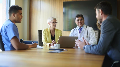 
                a group of people having a meeting around a table
              