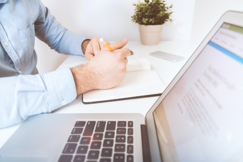 
                      a person sitting at a table with a notebook and laptop
                    