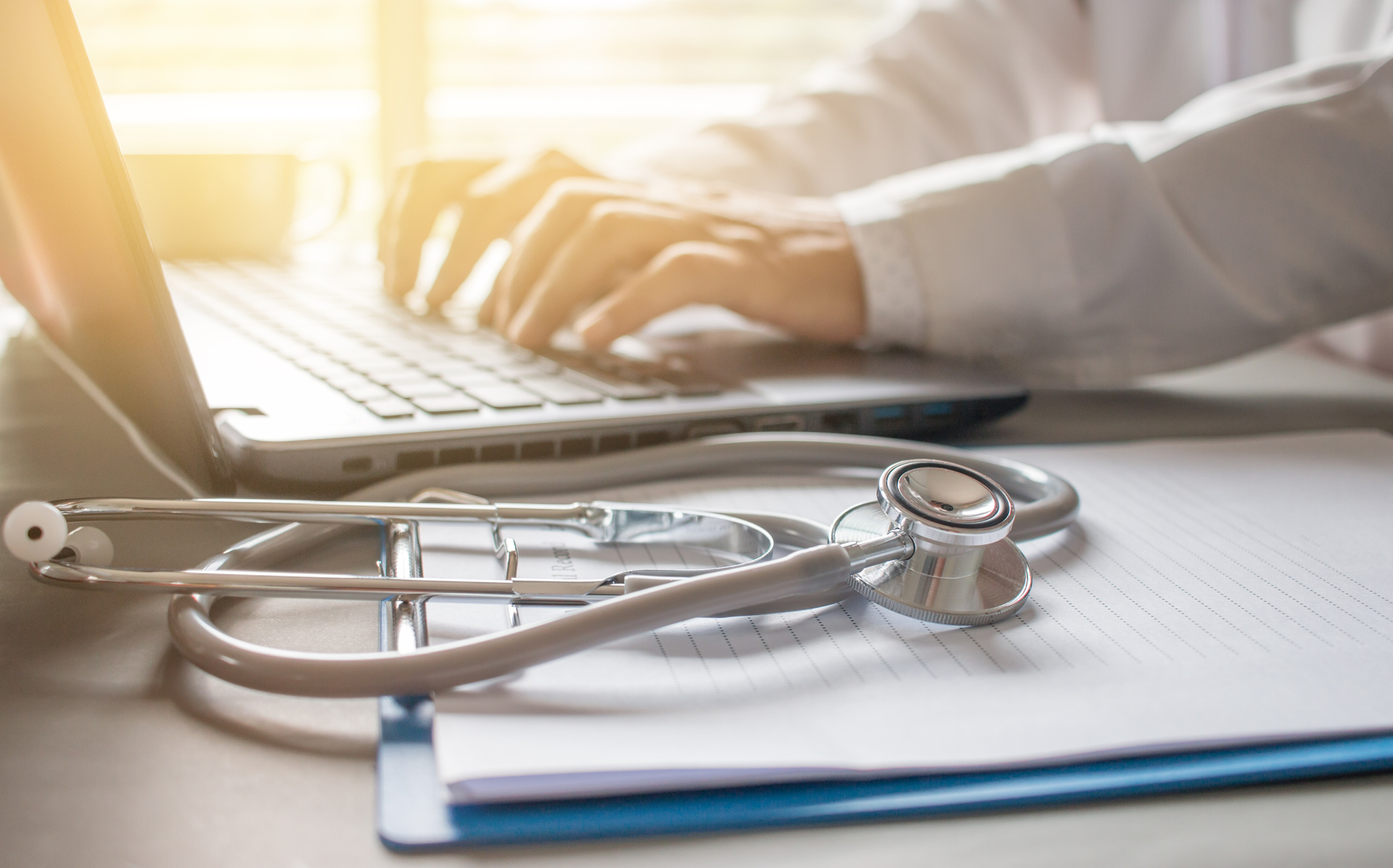 
                a stethoscope on a clipboard beside a laptop being used
              